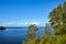 Beautiful view of a lake with white clouds in the blue sky. Green pines in the foreground, juicy, summer background of Karelian