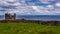 Beautiful view of a limestone fence with the ruined castle tower and the Atlantic Ocean in the background