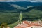 A beautiful view of the long road leading from the town with red tiled roofs far away to the horizon with green hills.