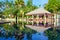 Beautiful view on luxury swimming pool. Chairs, umbrella and palm trees reflected in water