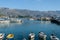 Beautiful view of moored fishing boats in marina harbor of Mediterranean city Budva, Montenegro. Scenic mountains background.