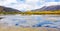 Beautiful view of natural lake with water reflection of bright sky, autumn forest trees and mountains background. Scenic Trip to T