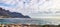 Beautiful view of the ocean and mountains in Cape Town. Water, waves and rocky planes along the coast. Cloudy sky on top