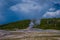 Beautiful view of old faithful Geyser Basin located in Yellowstone National Park, surrounded by vapor with a green