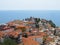 Beautiful view of the old Greek city with red tiled roofs temple and endless blue sea on a hot Sunny summer day