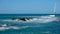 Beautiful view of the Pacific coast with black lava reefs and a small house with a huge wind generator in the distance on the Sout