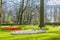 Beautiful view of a park with green grass, trees, paths and red, white, yellow and lilac flowers