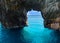 Beautiful view on rock arces arches of Blue caves from sightseeing boat with tourists in blue water of Ionian Sea inside cave, Isl