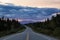 Beautiful View of a scenic road, Alaska Hwy, in the Northern Rockies during a dramatic cloudy sunset.