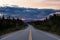 Beautiful View of a scenic road, Alaska Hwy, in the Northern Rockies during a dramatic cloudy sunset.