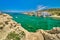 Beautiful view of secluded Mediterranean island bay on summer day. Whitewashed houses, hills, clear sky, azure sea