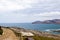 Beautiful view on the shore sea in La Pelosa Beach. Gray hills, blue water and sky with clouds, road going along the sea in