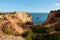 Beautiful view of small canyon with red-coloured rocks and hideaway beach. Algarve region, Portugal