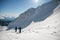 beautiful view of the snow-capped mountain slope and skiers with backpacks and skis on their backs