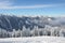 Beautiful view of the snow-covered spruces, mountains and low clouds in winter