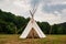 Beautiful view of the summer wedding tipi in a field. Tee pee built on green grass. Traditional teepee tent wigwam located in