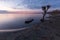 Beautiful view of Trasimeno lake Umbria at dusk, with a little boat near a bare tree, perfectly still water and a