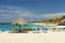 Beautiful view of white sand Curacao beach. Blue sunbeds under sun umbrellas on turquoise water and blue sky.