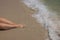 Beautiful view of woman\'s legs being caressed by waves of Atlantic Ocean on sandy shores