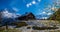 Beautiful view of a wooden building on the snowy hill surrounded by the rocky Alps