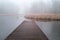 Beautiful view of a wooden jetty by the lake on a misty day