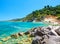 Beautiful view on Zakynthos stone and sand beach, stone rocks, swimming and toasting people on the beach, blue ultramarine water o