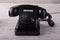 Beautiful vintage black telephone on a wooden table with white shabby paint.