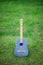 Beautiful vintage jeans acoustic classical guitar with nylon strings with wooden neck standing on vivid green grass