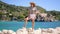 Beautiful warm summer scene - woman in striped t-shirt and hat standing on turquoise sea and mountains background. Girl