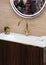 A beautiful washbasin with a gold tap and fittings. Marble sink, round led mirror, gold dispenser