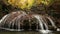 Beautiful waterfall flowing in the autumn forest with fallen leaves