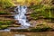 Beautiful waterfall in a mountain stream in the forest. One of the waterfalls of the cascade of Rusiliv waterfalls. Rusyliv,