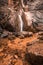 Beautiful waterfall with trees, red leaves, rocks and stones in autumn forest