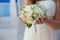 Beautiful wedding bouquet in hands of the bride. Gold ring and white dress