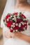 Beautiful wedding bouquet of red roses flowers in hands of anonymous young bride