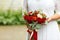 Beautiful wedding bouquet of red roses and red Hypericum berries in hands of bride