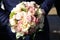 Beautiful wedding bouquet of roses in the hands of a man in a blue suit. Details of the wedding ceremony. Groom bride. Gay