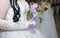 Beautiful wedding crystal glass decorated with a bead and a satin ribbon in the hands of the bride against the background of a whi