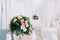 Beautiful wedding floral decoration on a table in a restaurant. White tablecloths, bright room, candles, close-up shooting. The ev