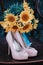 Beautiful wedding shoes with high heels and a bouquet of sunflowers on a vintage chair