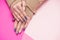 Beautiful well-groomed women`s hands with an interesting manicure on a pink background. Painted with modern gel-polish with top