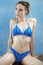 Beautiful wet oiled woman sitting in blue bikini in studio