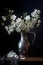 beautiful white apple blossom flowers in a vintage pewter jug. Dark and moody still life