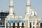 A beautiful white and blue mosque with multiple domes and minarets against blue summer sky