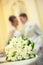 Beautiful white bouquet of flowers on the background of a blurred silhouette of a loving couple of bride and groom.