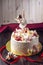 Beautiful white cake decorated with a figurine of a dancing ballerina, strawberry and marshmallow on top