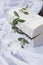 Beautiful white casket in a vintage style of standing on a white cloth with a sprig of a tree on the cover