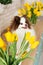Beautiful white chocolate spitz in the kitchen among yellow tulips. national dog day. a pet. spring decor. women`s Day.