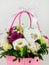 Beautiful white Eustoma Gypsophila flowers bouquet in pink pastel basket dark background. Floral gift blooming wallpaper