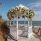 Beautiful white gazebo on the beach by the sea, twined with white rose flowers, a beautiful place for special occasions,